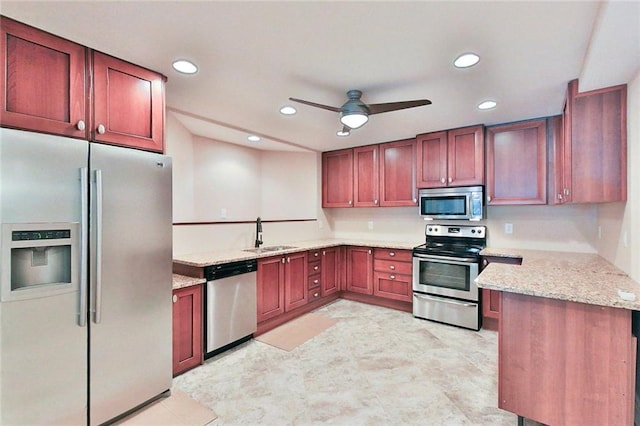 kitchen with appliances with stainless steel finishes, kitchen peninsula, sink, ceiling fan, and light stone counters