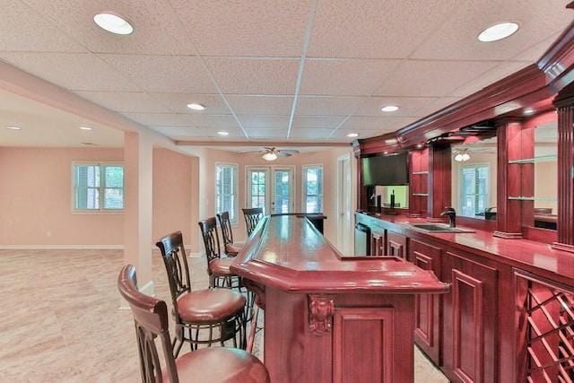 bar with a drop ceiling, sink, a wealth of natural light, and french doors