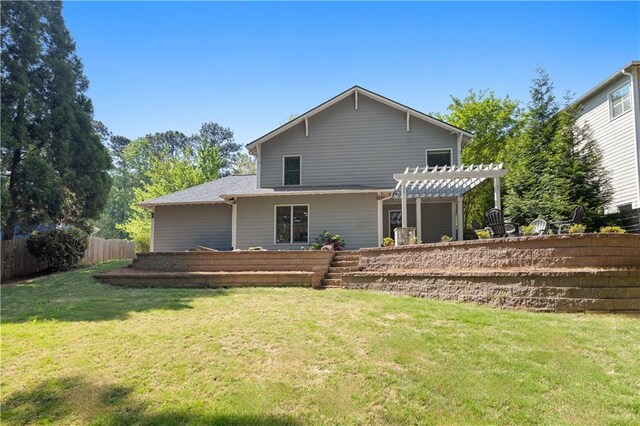 rear view of house with a pergola, a yard, and fence