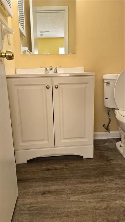 bathroom with vanity, toilet, and hardwood / wood-style floors