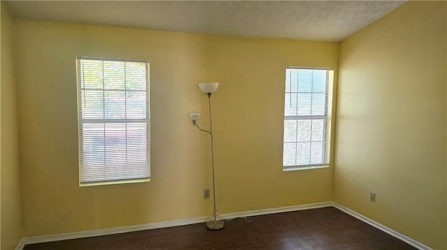 empty room with a textured ceiling and dark hardwood / wood-style flooring