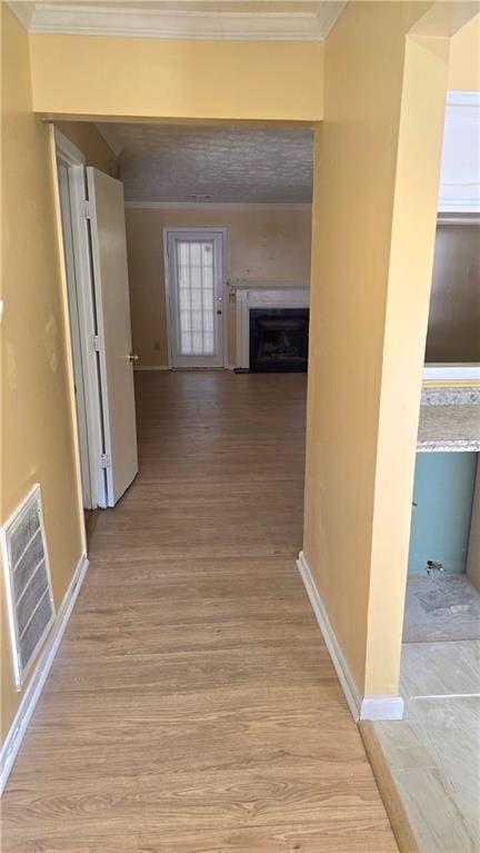 hallway with crown molding and light hardwood / wood-style floors