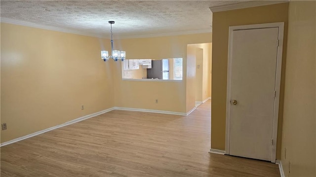 spare room with ornamental molding, a chandelier, light hardwood / wood-style flooring, and a textured ceiling