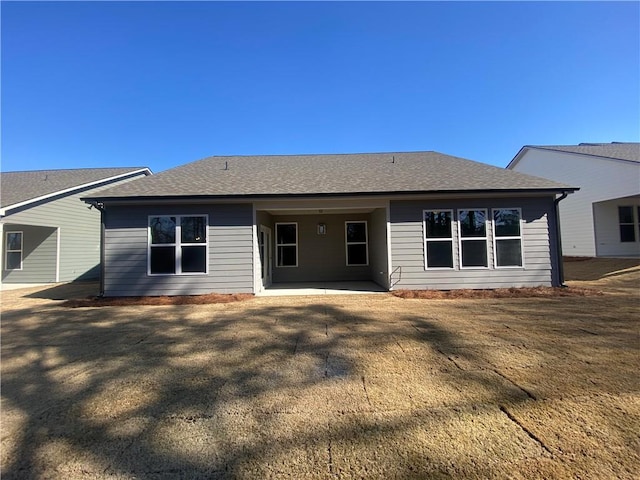 rear view of house with a patio and a shingled roof