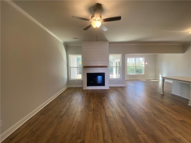 unfurnished living room featuring a large fireplace, dark wood-type flooring, crown molding, baseboards, and a ceiling fan