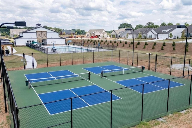 view of tennis court featuring a residential view and fence