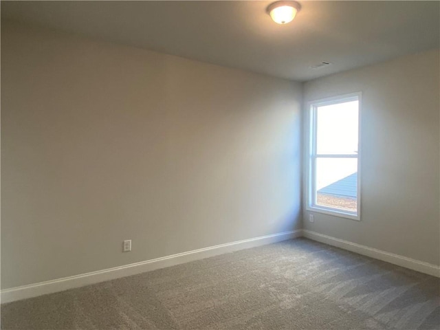 empty room with baseboards and dark carpet