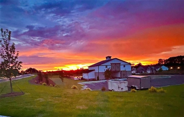 back of property at dusk featuring a lawn