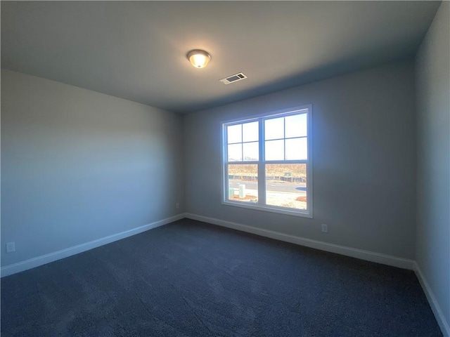 empty room with visible vents, dark carpet, and baseboards