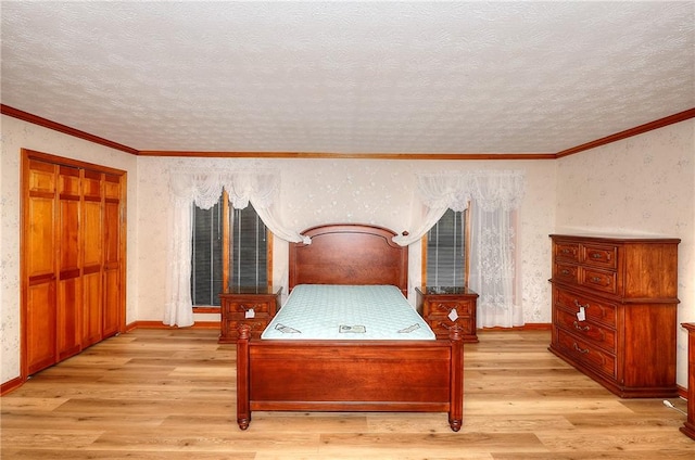 bedroom with a textured ceiling, light wood-type flooring, crown molding, and a closet