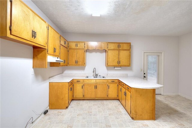 kitchen with sink, kitchen peninsula, and a textured ceiling