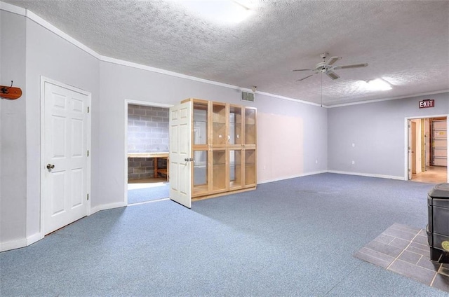 empty room featuring a wood stove, ceiling fan, and a textured ceiling