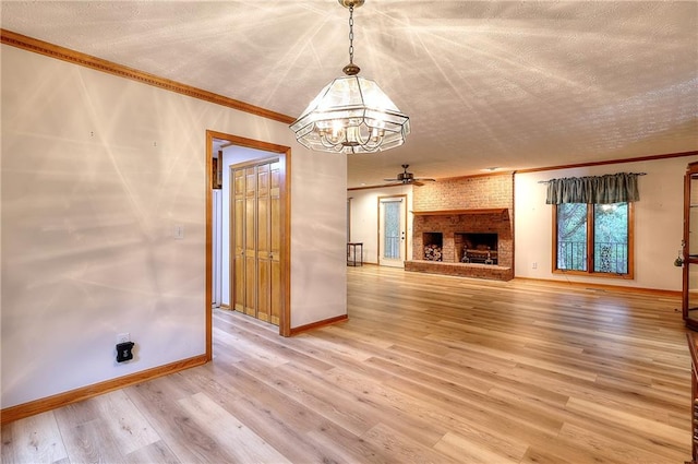 unfurnished living room with ceiling fan with notable chandelier, a brick fireplace, a textured ceiling, and hardwood / wood-style floors