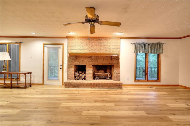 living room with ceiling fan, ornamental molding, a brick fireplace, a textured ceiling, and hardwood / wood-style flooring