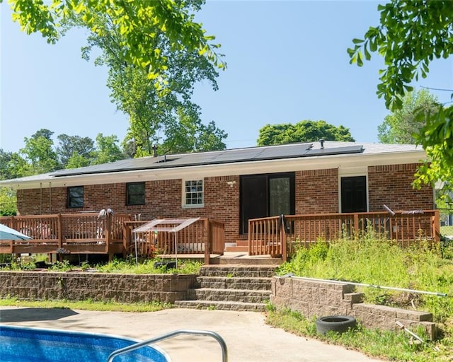 724 Camelot Way, Norcross, GA 30071 - rear view of property with solar panels, a deck, an outdoor pool, and brick siding