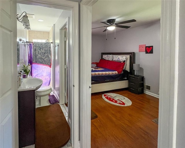 bedroom featuring ceiling fan, wood finished floors, a sink, and visible vents