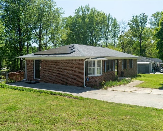exterior space featuring roof mounted solar panels, brick siding, fence, and a yard