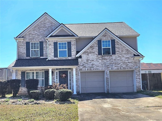 craftsman-style home featuring a garage, driveway, brick siding, and fence