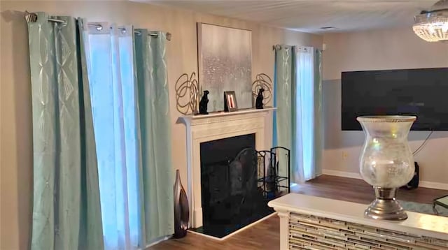 living area with a fireplace, baseboards, and wood finished floors