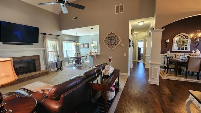 living area with wood finished floors, a fireplace, decorative columns, and visible vents