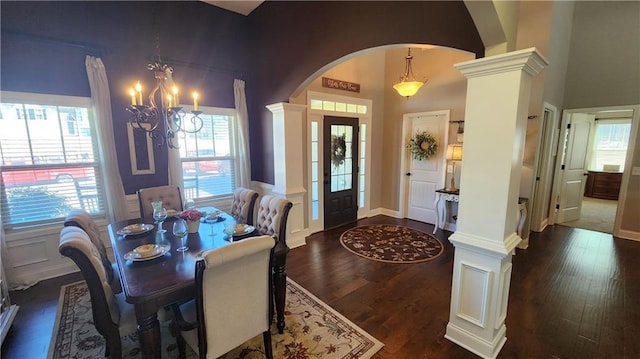 dining room featuring dark wood-style floors, arched walkways, a wainscoted wall, and ornate columns