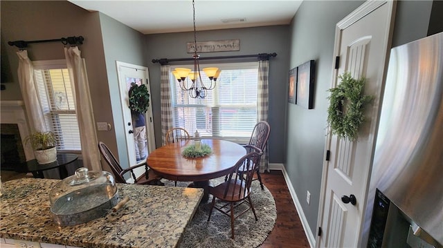 dining space featuring a fireplace, visible vents, baseboards, dark wood-style floors, and an inviting chandelier