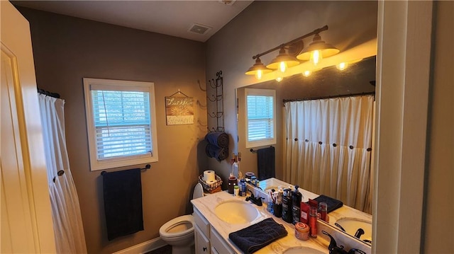 full bath featuring toilet, double vanity, a sink, and visible vents