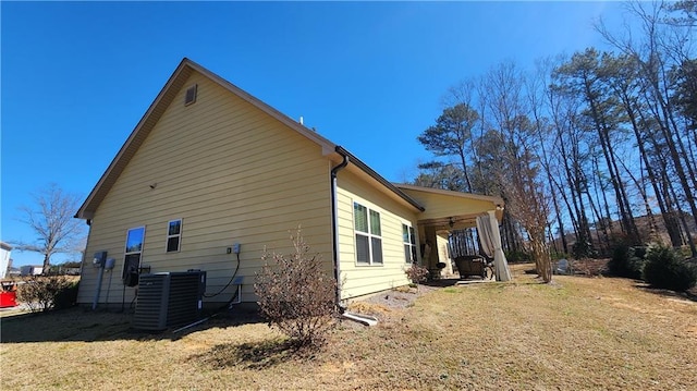 view of side of property with central air condition unit and a lawn