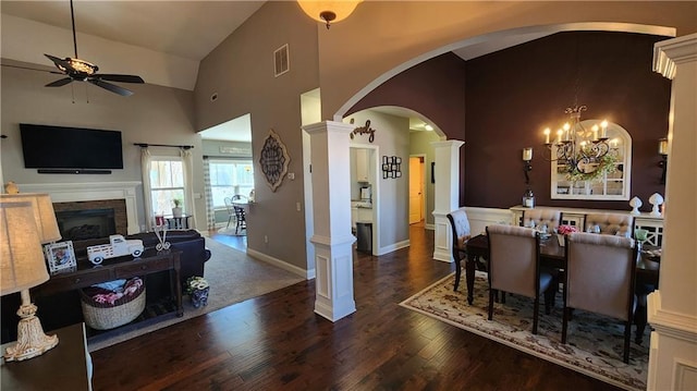 dining area with arched walkways, a fireplace, visible vents, wood finished floors, and high vaulted ceiling