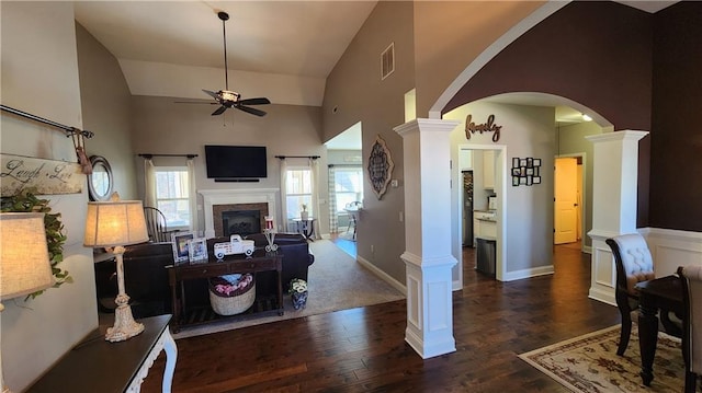 living room featuring decorative columns, a fireplace, arched walkways, and wood finished floors