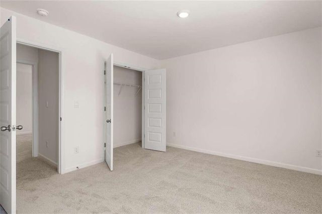 unfurnished bedroom featuring light colored carpet and a closet