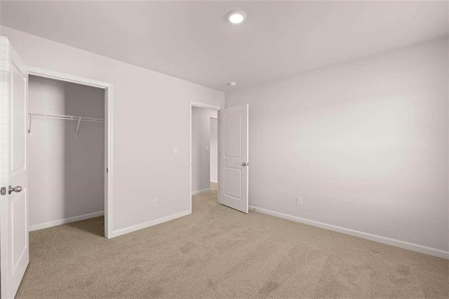 unfurnished bedroom featuring light carpet and a closet