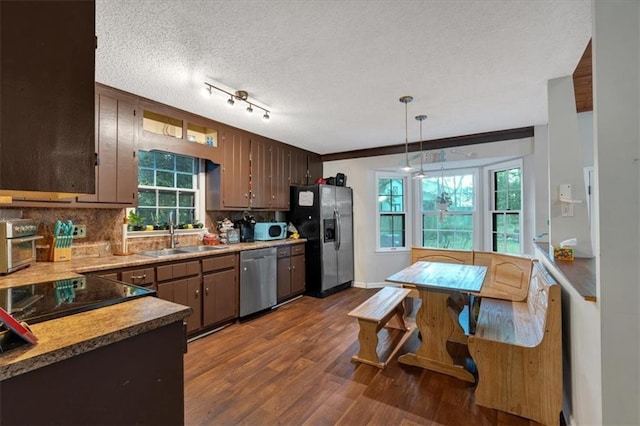 kitchen featuring dark hardwood / wood-style floors, sink, hanging light fixtures, appliances with stainless steel finishes, and a textured ceiling