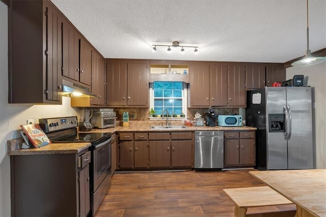 kitchen with dark wood-type flooring, decorative light fixtures, sink, stainless steel appliances, and a textured ceiling