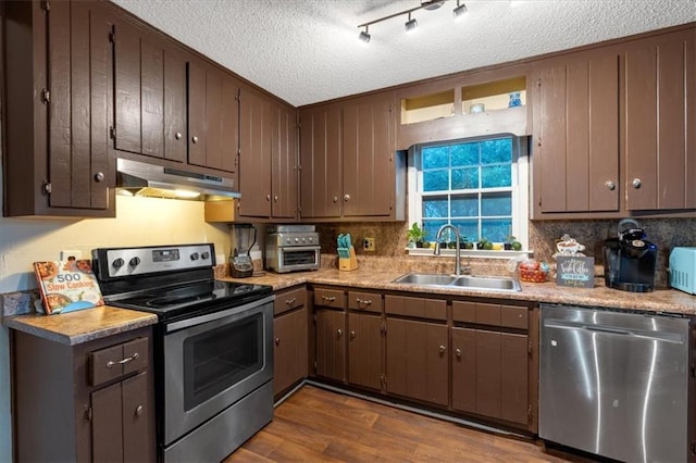 kitchen with dark wood-type flooring, sink, decorative backsplash, appliances with stainless steel finishes, and a textured ceiling