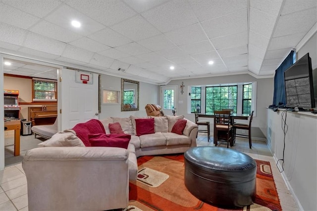 living room with light tile patterned floors, a drop ceiling, and ornamental molding