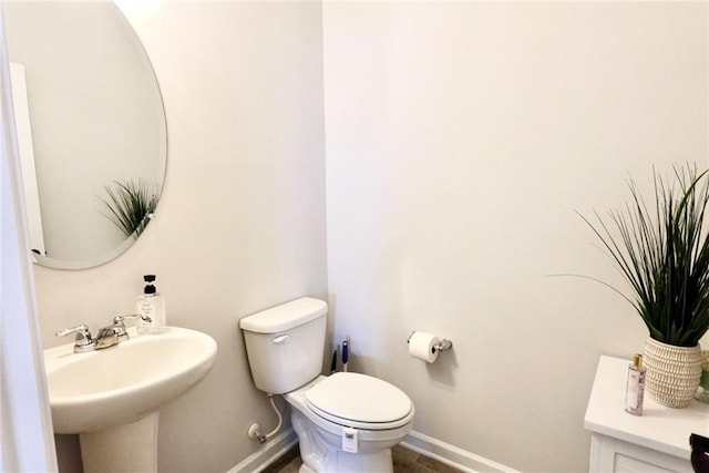 bathroom featuring toilet, baseboards, and a sink