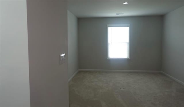 carpeted spare room featuring visible vents and baseboards