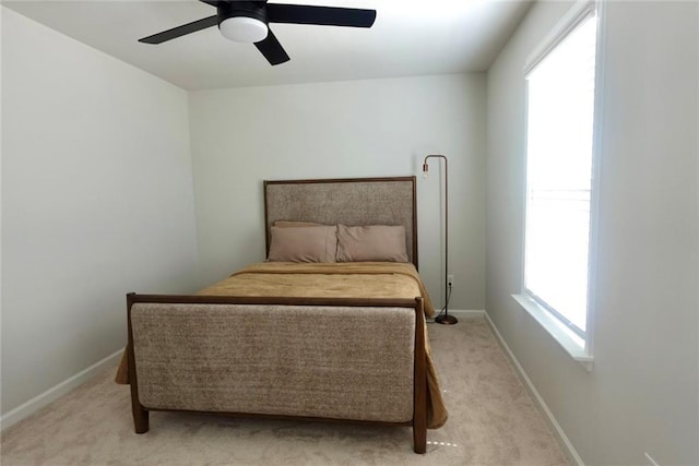 bedroom featuring light carpet, a ceiling fan, and baseboards