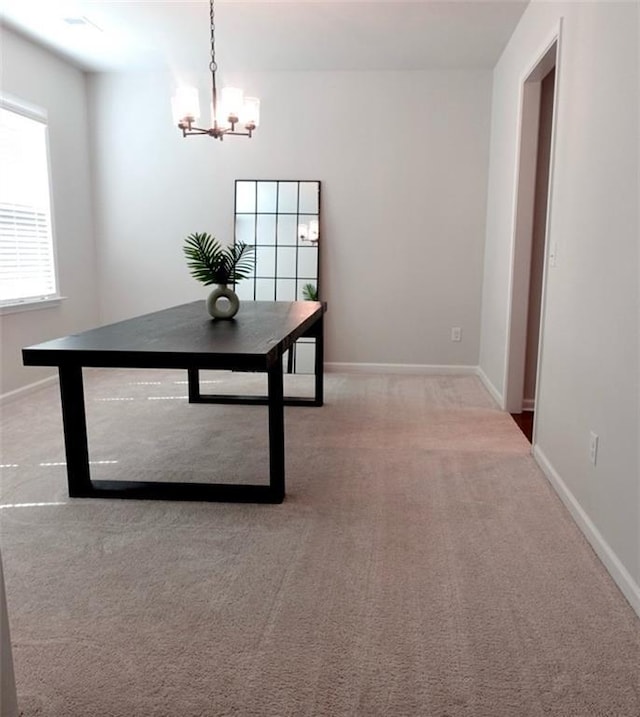 unfurnished dining area featuring light colored carpet, baseboards, and a chandelier