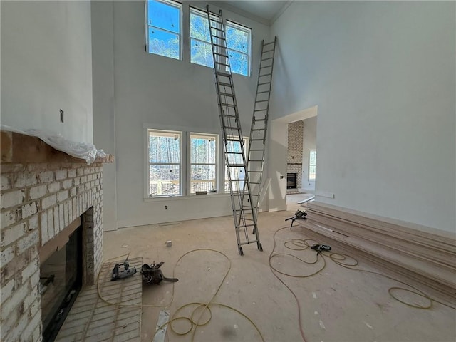 unfurnished living room featuring a high ceiling, plenty of natural light, and a fireplace