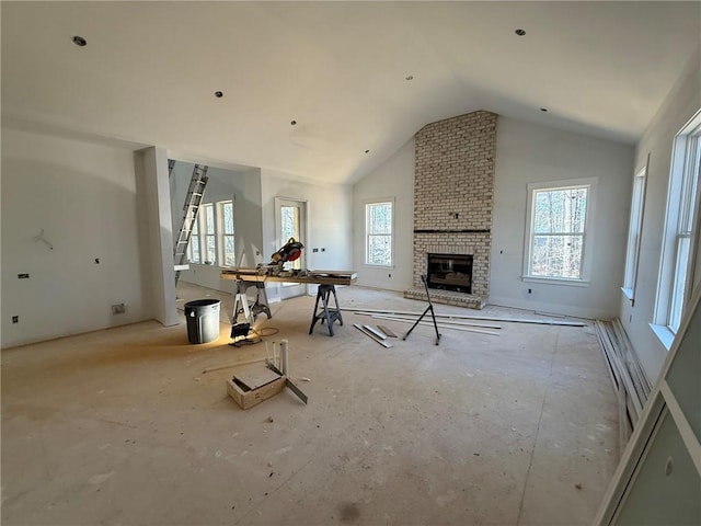 unfurnished living room with plenty of natural light, high vaulted ceiling, and a brick fireplace