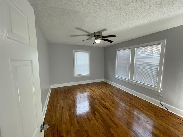 spare room featuring dark wood-type flooring, a textured ceiling, and ceiling fan