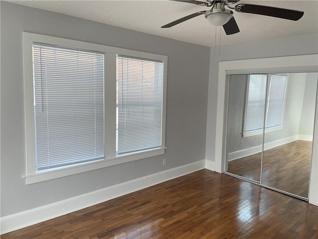 unfurnished bedroom with ceiling fan, dark hardwood / wood-style floors, a closet, and a textured ceiling