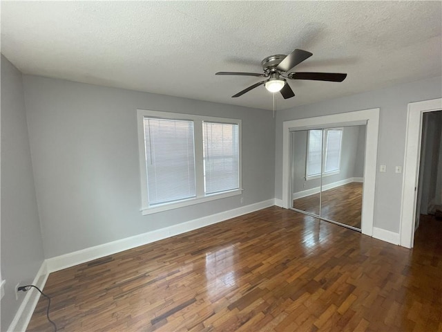 unfurnished bedroom with dark hardwood / wood-style floors, a textured ceiling, ceiling fan, and a closet