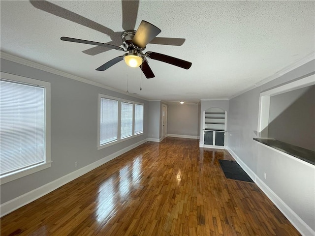 unfurnished living room featuring dark wood-type flooring, ornamental molding, and a textured ceiling