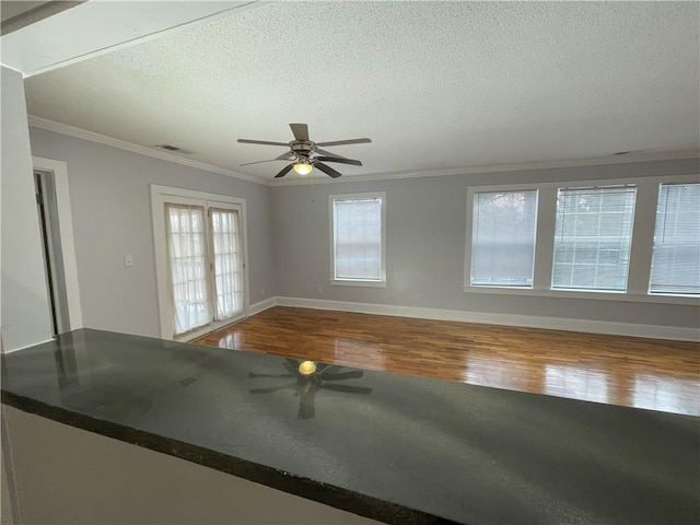 empty room with hardwood / wood-style flooring, a healthy amount of sunlight, crown molding, and a textured ceiling