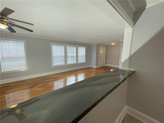 interior space with wood-type flooring, ornamental molding, and a textured ceiling