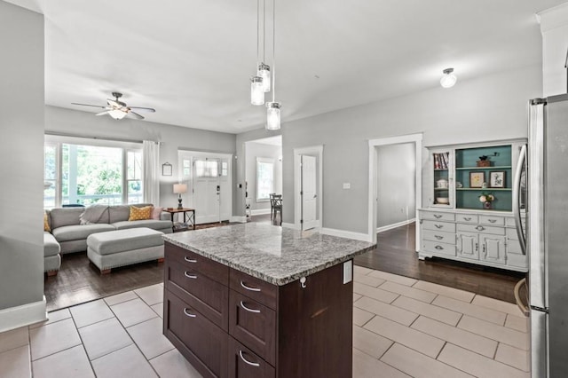 kitchen with ceiling fan, light tile floors, hanging light fixtures, a center island, and stainless steel refrigerator