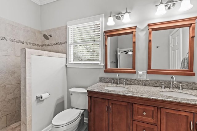 bathroom with ornamental molding, double sink, vanity with extensive cabinet space, ceiling fan, and toilet